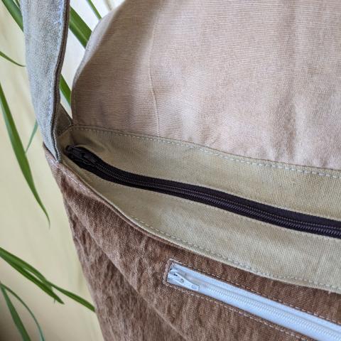 detail of the eco-printed messenger bag, showing the zipper closure and pocket