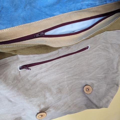 detail of the eco-printed messenger bag, showing the zipper closure and pocket