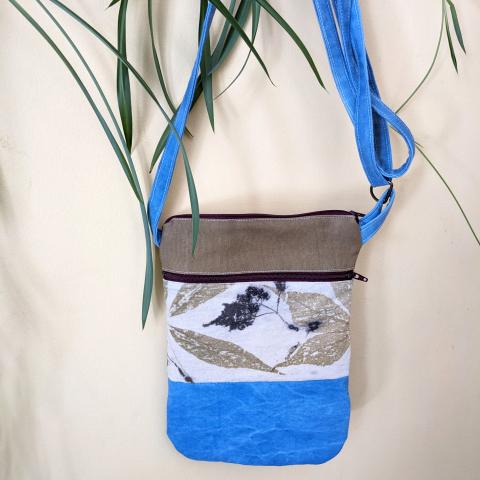 A naturally dyed small essentials crossbody bag, hanging on a wall